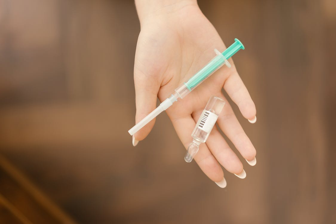 a hand holding a syringe and a vial